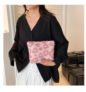 Detail showing a pink heart pattern plush cosmetic bag being held in a lifestyle setting