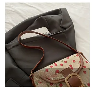 Détail du sac à bandoulière imprimé cerises avec garniture en cuir et boucle dorée
