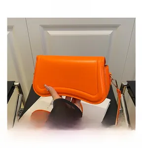Detail of orange leather shoulder bag with curved flap and Fashion & Bags gold text