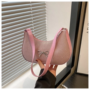 Macro view of pink rhinestone crescent bag with a decorative silver metal bow detail