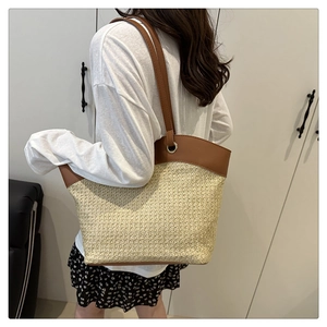 Model view showing the large straw woven tote bag with brown leather shoulder straps
