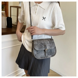 Retro grey saddle bag with distressed texture worn with a white knit top and pleated skirt