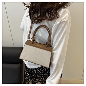 Close-up of canvas and leather patchwork handbag with gold fashion bag logo print