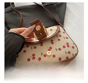 Détail du sac tricoté à motif cerise avec fermoir doré et finitions en cuir marron