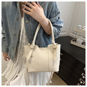 Close-up of litchi grain cream bucket bag with adjustable strap and gold hardware