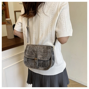 Detail of vintage dark grey saddle bag with buckle on casual white knitted outfit