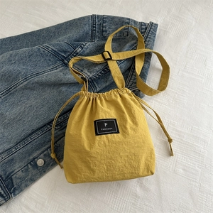 Close-up of bright yellow nylon bucket bag with logo and adjustable shoulder strap