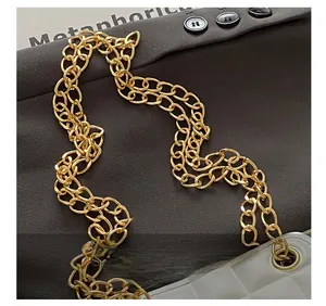 Détail de la bandoulière en chaîne dorée brillante sur un sac blanc matelassé élégant