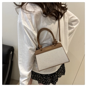 Détail du sac à bandoulière en toile avec bordure en cuir marron et poignée nouée