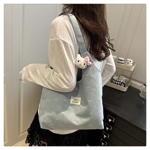 Light blue canvas tote bag featuring white bows, dot patterns, and a cute plush charm