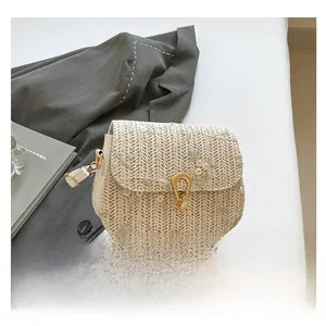 Close-up of handmade straw saddle bag with floral embroidery and golden metal buckle