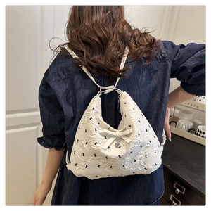 Détail du sac à dos matelassé blanc avec nœud et breloque cœur sur chemise denim