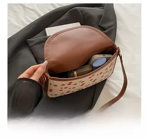 Capacité interne du sac à bandoulière motif cerises montrant smartphone et portefeuille