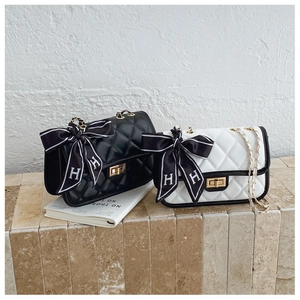 Detail of quilted chain bag featuring H-pattern silk scarf and gold metal twist lock