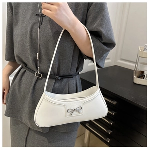 Detail of a white crescent shoulder bag with silver bow accent on a model