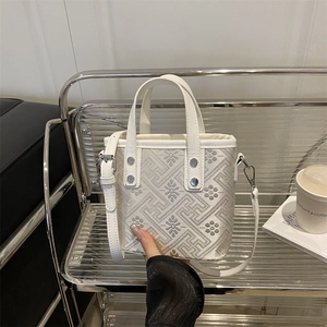 Elegant white checkered bucket bag with floral patterns on a silver display stand