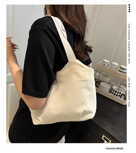 Minimalist beige canvas tote bag shown from side view on person for daily commuting use