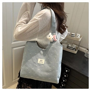 Detail of light blue tote bag with white bow prints and a cute plush kitten charm