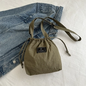 Detail of army green nylon bucket bag featuring a drawstring closure and brand label