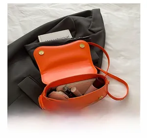 Detail view of orange leather shoulder bag showing interior space for phone and makeup