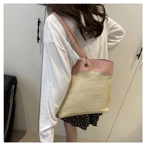 Close-up of pink leather handles on a beige straw woven tote bag for summer