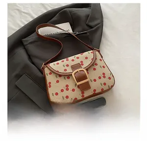 Détail du sac en toile à imprimé cerises avec finitions en cuir et boucle dorée