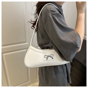 Detail of white PU leather crescent bag featuring a silver metal bow accent