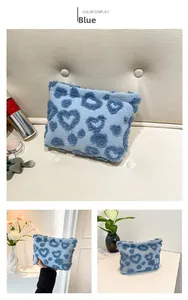 Detailed view of a soft blue plush makeup pouch featuring cute dark blue heart patterns