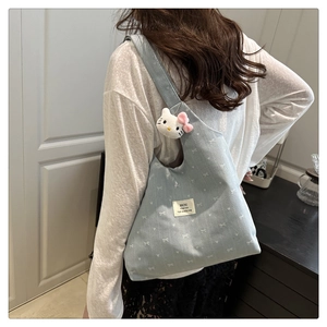 Detail of light blue hobo bag with white bow pattern and cute kitty plush charm accessory