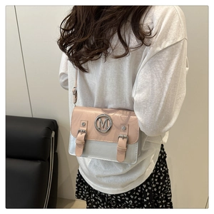 Close-up of a pink and silver crossbody bag with metal M logo and strap detail