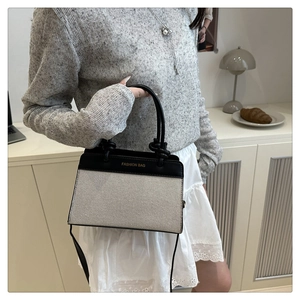 Detail of minimalist contrast shoulder bag featuring white canvas and black leather trim