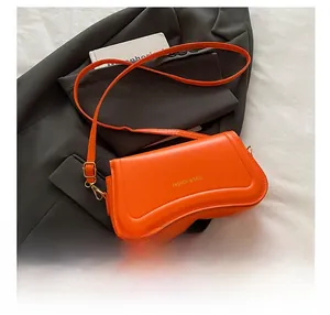 Orange leather shoulder bag with golden logo and smartphone for size comparison