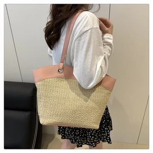 Detail view of woven straw tote bag with pink faux leather stitching and metal rings