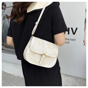 Detail of cream saddle bag featuring vintage belt buckle and high-quality synthetic leather