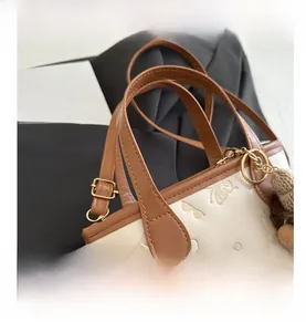 Detail of cream mini bucket bag featuring butterfly embossing and brown bear charm