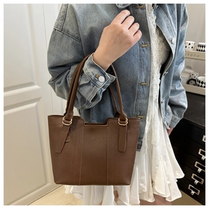Close-up of brown litchi pattern leather tote bag with elegant metal ring handles