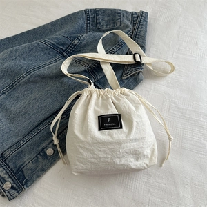 Detail of white nylon drawstring bucket bag with FANYISSA logo patch on fabric