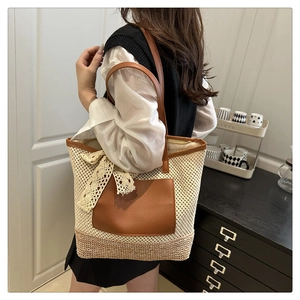 Detail of woven straw tote bag featuring leather straps and delicate lace bow decoration