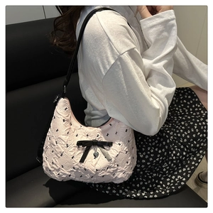 Détail du sac bandoulière rose matelassé avec nœud noir et pendentif cœur argenté