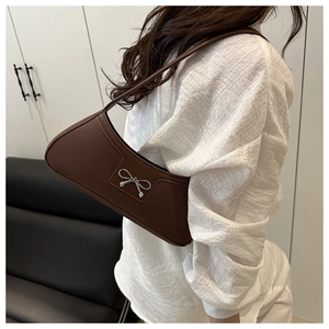 Detail of dark brown leather underarm bag with a silver bow buckle and sleek moon shape