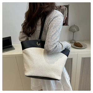 Detail of contrast stitch woven tote bag with leather straps and gold metal ring hardware
