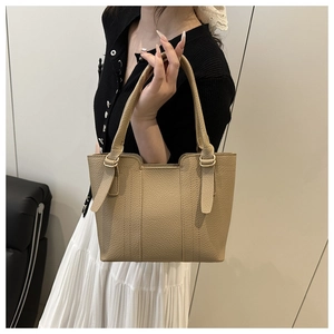 Detailed view of beige pebble leather bucket bag with vertical stitching and gold hardware