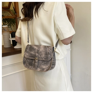 Detail of vintage saddle bag with flap closure and belt buckle on a coffee shop model