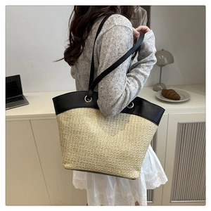 Detail of contrast stitching and metal ring on straw and leather shoulder tote bag
