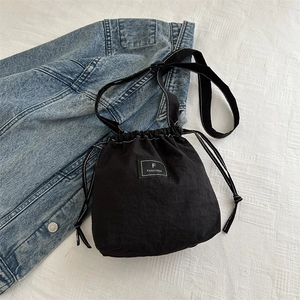 Detailed top view of a black nylon drawstring bucket bag with a stitched logo label