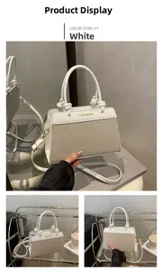 Detail view of white leather and canvas patchwork handbag with golden fashion text
