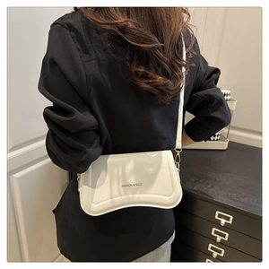 Back view of minimalist cream shoulder bag with wave bottom and gold hardware details