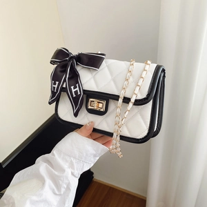 Quilted crossbody bag in white and black with chain strap and bow accessory