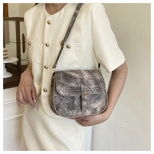 Detail of vintage marble pattern saddle bag with gold buckle on a cream blazer dress