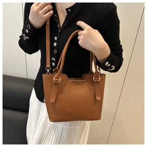 Detailed macro of brown lychee grain leather tote bag with gold metal hardware